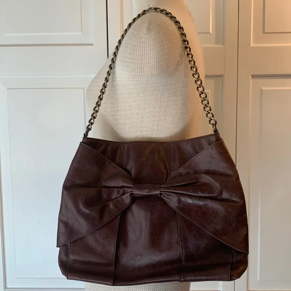 Hobo brown leather purse with bow on front and brass looking chain strap